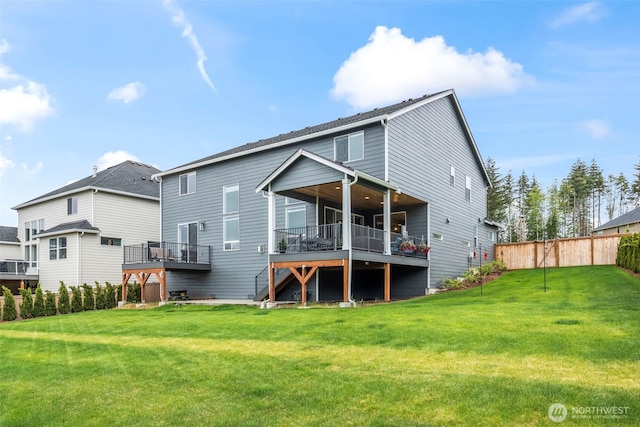 rear view of house featuring a lawn, a deck, and fence