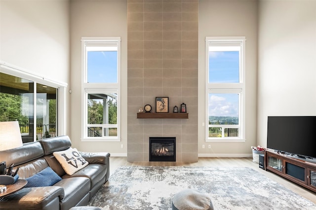 living area featuring a towering ceiling, a healthy amount of sunlight, and a fireplace