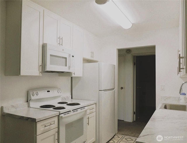 kitchen with a sink, light countertops, white appliances, and white cabinetry