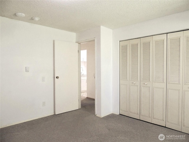 unfurnished bedroom featuring carpet floors, a textured ceiling, and a closet