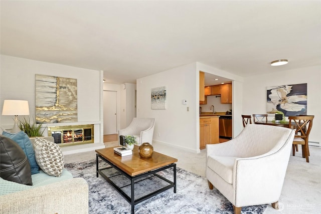 living room featuring baseboards, a glass covered fireplace, and light colored carpet