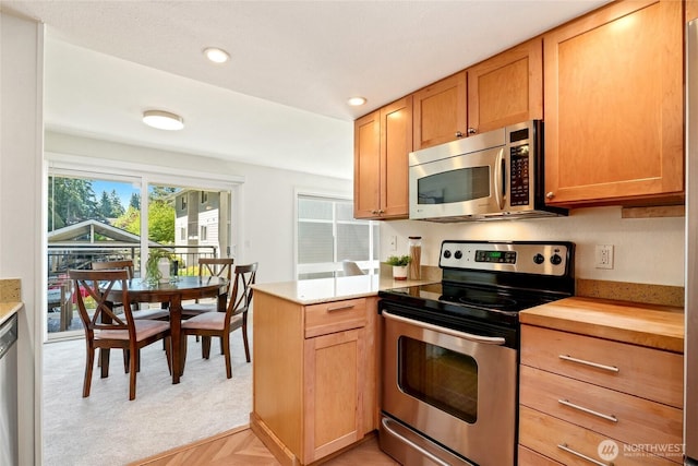 kitchen featuring butcher block countertops, recessed lighting, a peninsula, light carpet, and stainless steel appliances