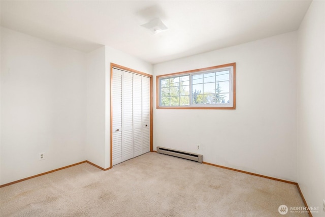 unfurnished bedroom with a closet, baseboards, carpet, and a baseboard radiator