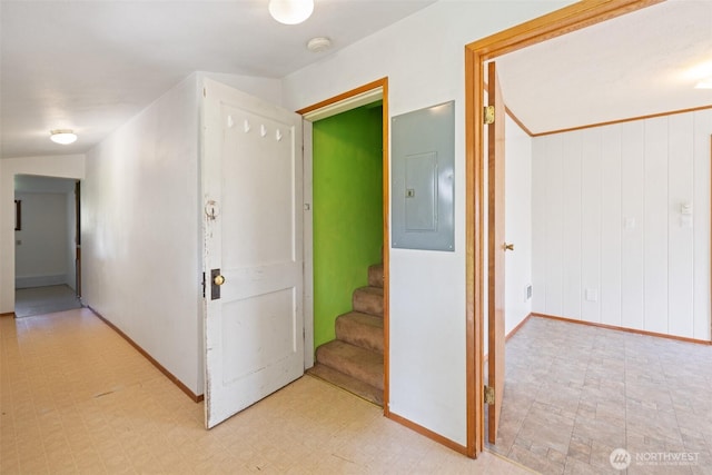 hallway with light floors, stairway, electric panel, and baseboards