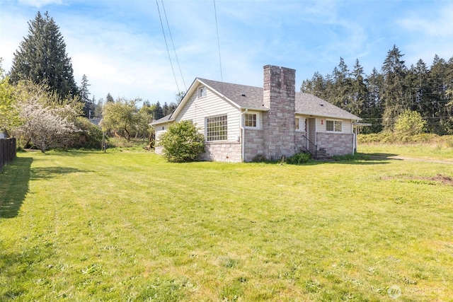 view of side of home featuring fence, a yard, and a chimney