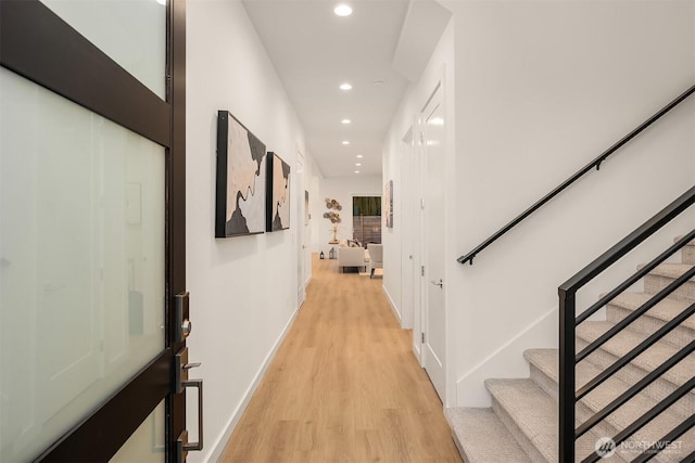 corridor featuring baseboards, recessed lighting, light wood-style floors, and stairway