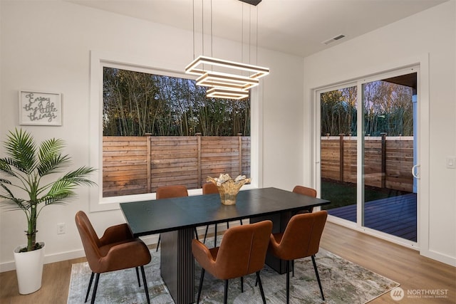 dining space with visible vents, an inviting chandelier, wood finished floors, and baseboards