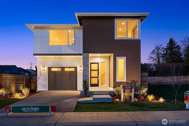 modern home featuring fence, driveway, and an attached garage