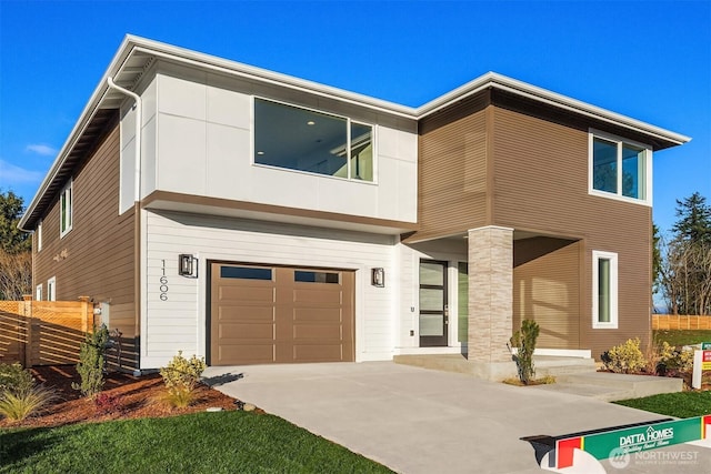contemporary house with fence, concrete driveway, and a garage