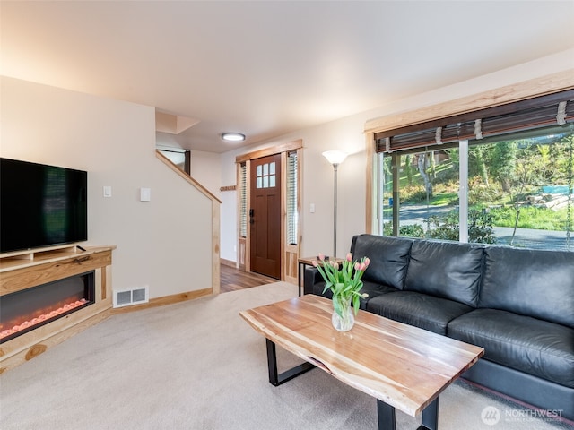 living room with baseboards, visible vents, carpet, and a glass covered fireplace