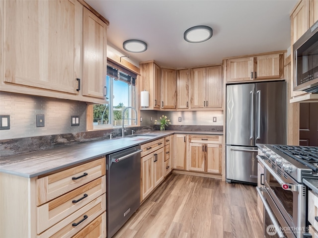 kitchen with light brown cabinetry, high quality appliances, light wood-style flooring, and a sink