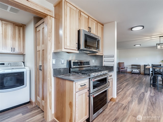 kitchen with washer / clothes dryer, appliances with stainless steel finishes, visible vents, light brown cabinets, and wood finished floors