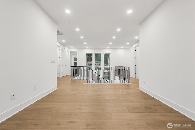 empty room with light wood-style floors and recessed lighting
