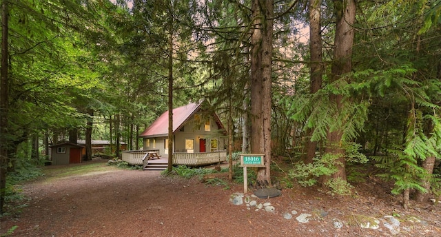 18016 Glacier Rim Dr, Glacier, WA 98244 - chalet / cabin featuring a wooden deck, a storage unit, metal roof, an outbuilding, and a forest view