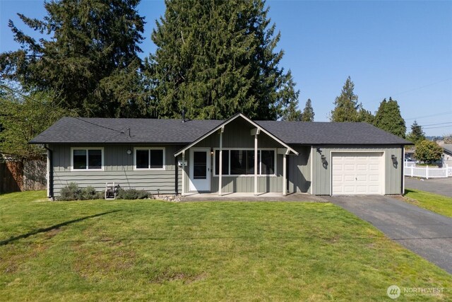 ranch-style home with a garage, fence, driveway, and a front lawn