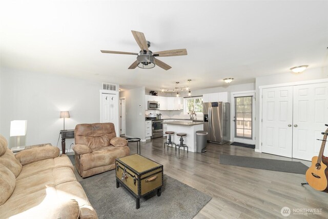 living room featuring visible vents, a ceiling fan, rail lighting, and dark wood-type flooring