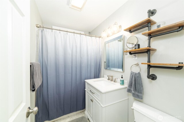 bathroom featuring toilet, curtained shower, and vanity