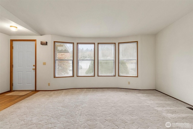 empty room with baseboards and light colored carpet