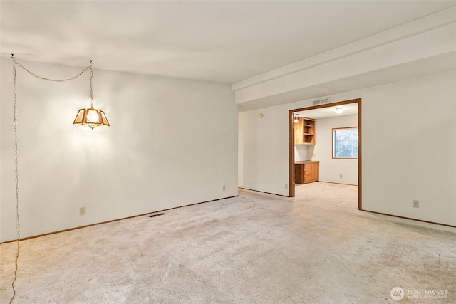 empty room with visible vents, baseboards, and light colored carpet