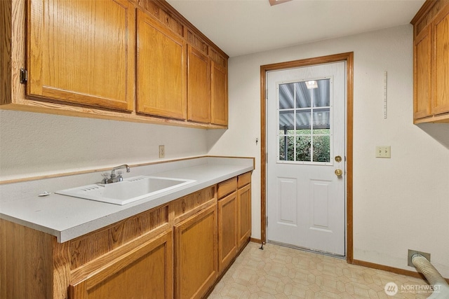 laundry area featuring baseboards, cabinet space, and a sink