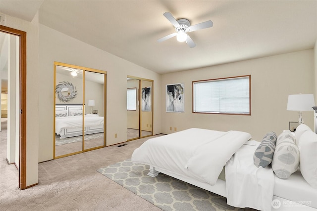 bedroom featuring lofted ceiling, carpet, multiple closets, and a ceiling fan