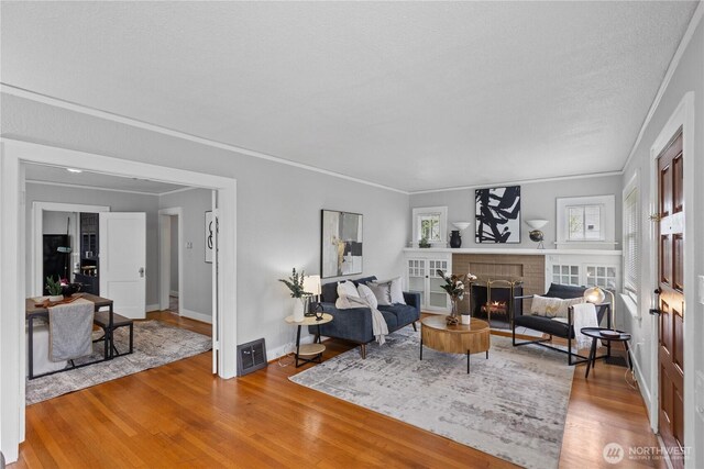 living area with plenty of natural light, ornamental molding, baseboards, and wood finished floors