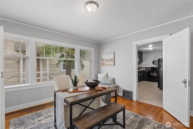 home office with a textured ceiling, visible vents, wood finished floors, baseboards, and ornamental molding