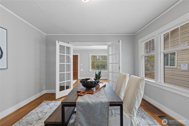 dining space featuring french doors, ornamental molding, baseboards, and wood finished floors