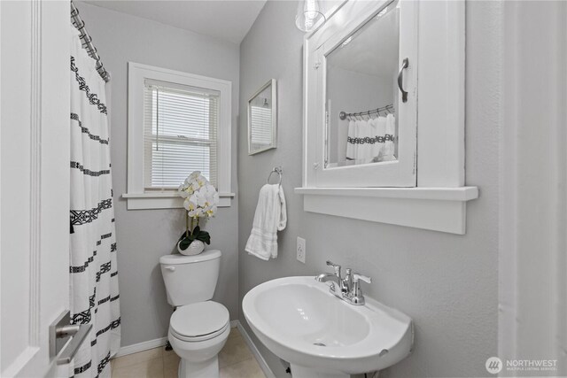 bathroom featuring a sink, toilet, tile patterned floors, baseboards, and a shower with curtain