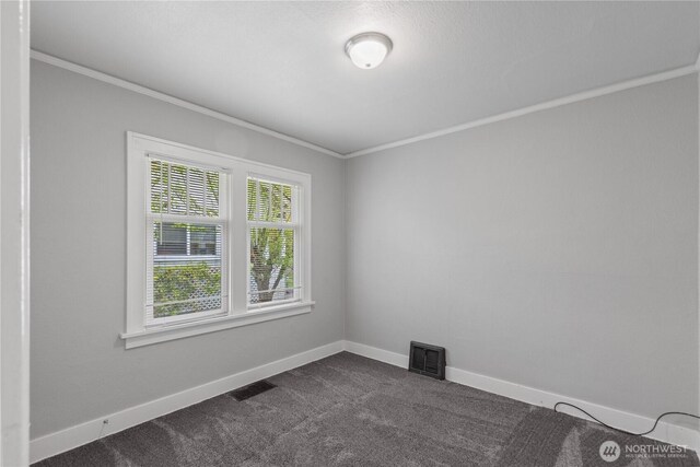 unfurnished room with crown molding, dark carpet, and visible vents