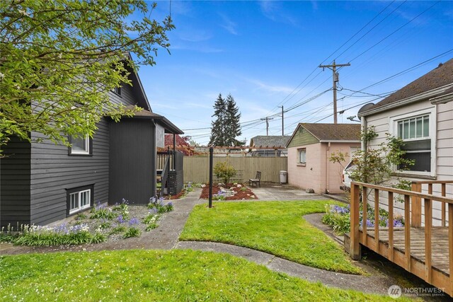 view of yard with an outdoor structure, a deck, fence, and a patio