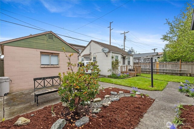 back of property featuring fence, a yard, and concrete block siding
