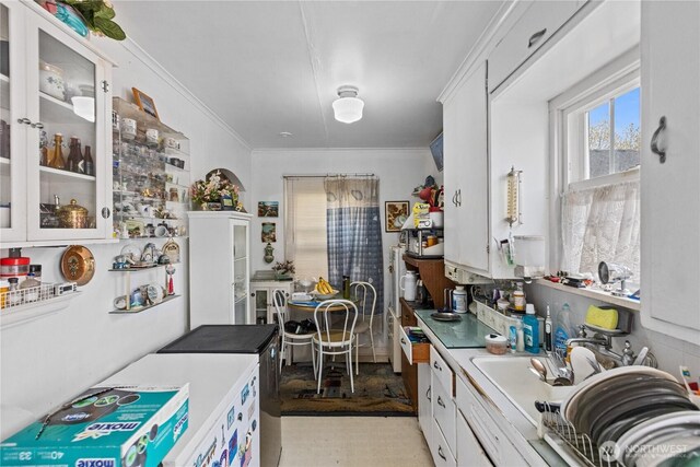 kitchen featuring crown molding, white cabinetry, glass insert cabinets, and light countertops