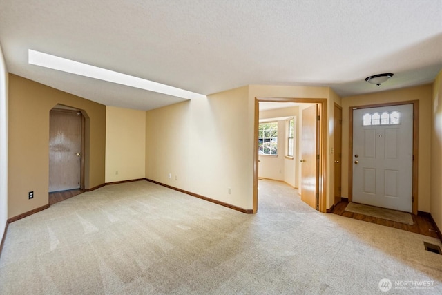 entrance foyer with baseboards, arched walkways, and carpet floors