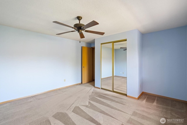 unfurnished bedroom featuring baseboards, ceiling fan, a closet, and carpet