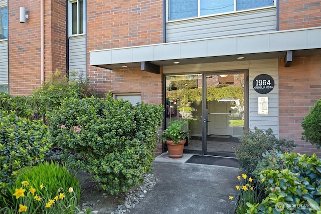 view of exterior entry featuring brick siding