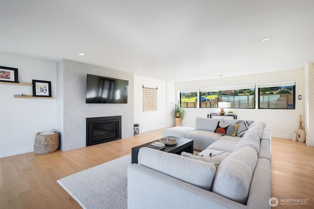 living room featuring baseboards, recessed lighting, wood finished floors, and a fireplace