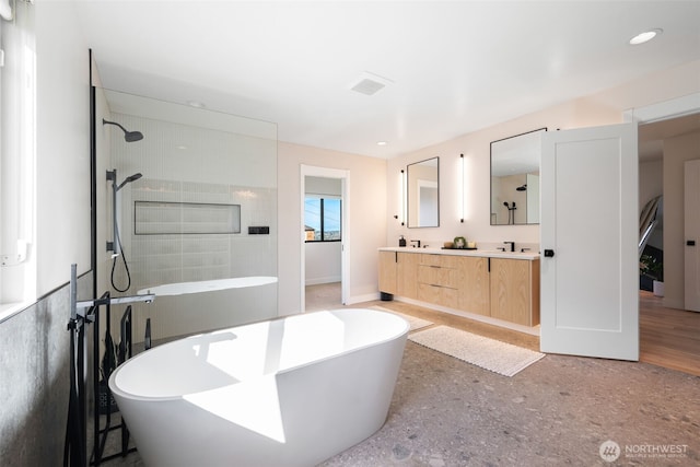full bathroom featuring baseboards, a walk in shower, double vanity, a sink, and a soaking tub