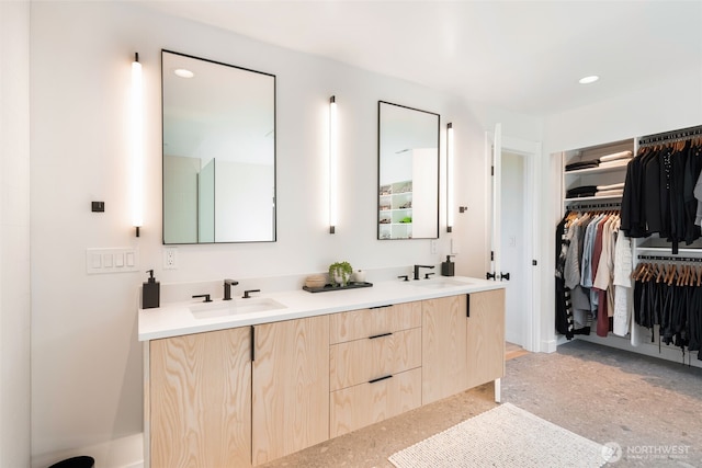 full bath with double vanity, a spacious closet, recessed lighting, and a sink