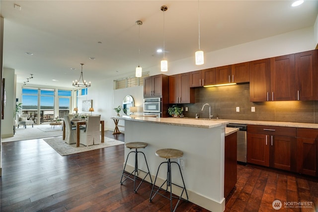kitchen featuring appliances with stainless steel finishes, backsplash, a chandelier, and dark wood-type flooring