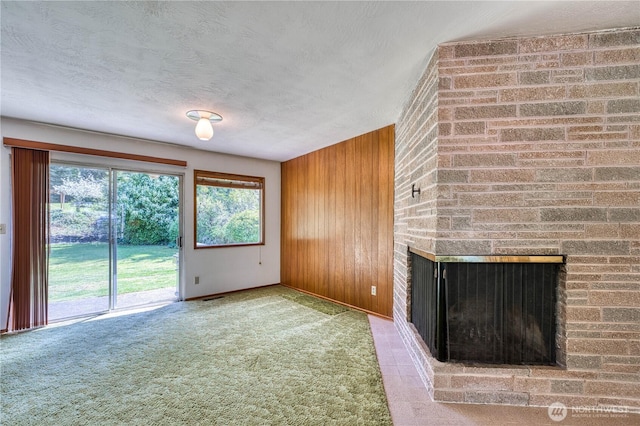3828 Harbel Dr NE, Bremerton, WA 98310 - unfurnished living room featuring a textured ceiling, carpet flooring, baseboards, wooden walls, and a brick fireplace