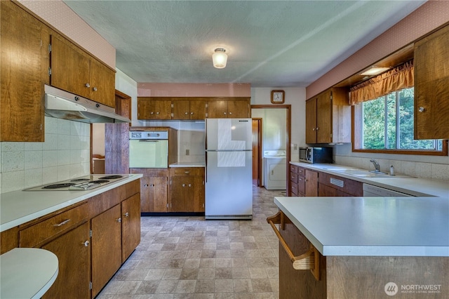 3828 Harbel Dr NE, Bremerton, WA 98310 - kitchen with washer / dryer, a sink, light countertops, under cabinet range hood, and white appliances