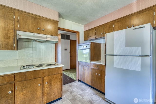 3828 Harbel Dr NE, Bremerton, WA 98310 - kitchen featuring brown cabinetry, light countertops, under cabinet range hood, and white appliances