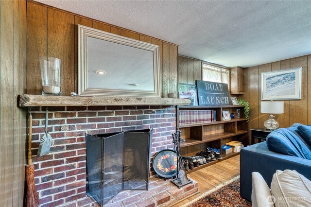 3828 Harbel Dr NE, Bremerton, WA 98310 - living room with wood walls, a textured ceiling, wood finished floors, and a fireplace