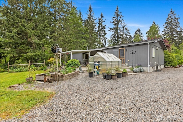 view of front facade featuring a garden, an exterior structure, an outbuilding, and a front lawn