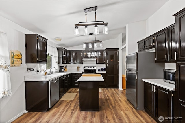 kitchen featuring stainless steel appliances, a kitchen island, light countertops, and wood finished floors
