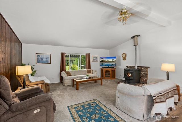 living area with lofted ceiling, carpet flooring, a wood stove, and a ceiling fan