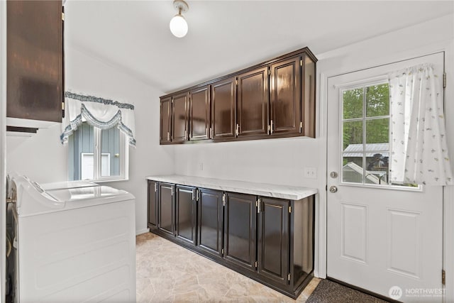 clothes washing area with cabinet space, washing machine and clothes dryer, and baseboards