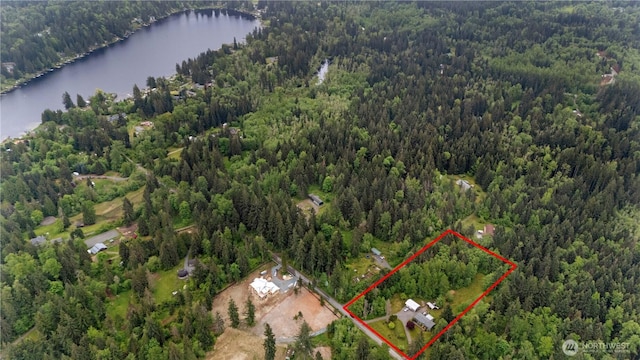 view of property location with a heavily wooded area, a large body of water, and property parcel outlined