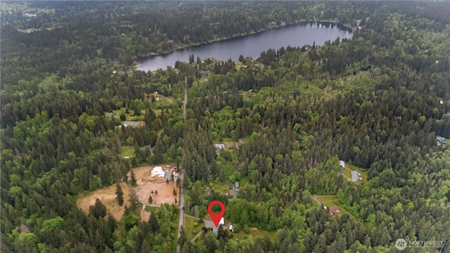 aerial view of property and surrounding area with a heavily wooded area and a nearby body of water